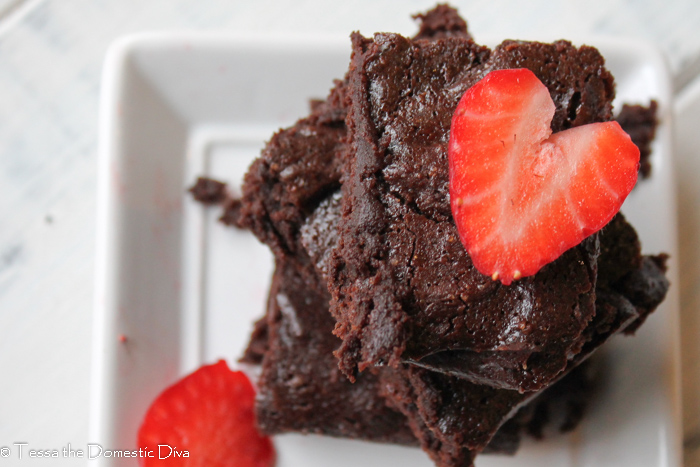 birds eye close up of a stack of cocoa powder brownies with a slice of strawberry in a heart shape on top