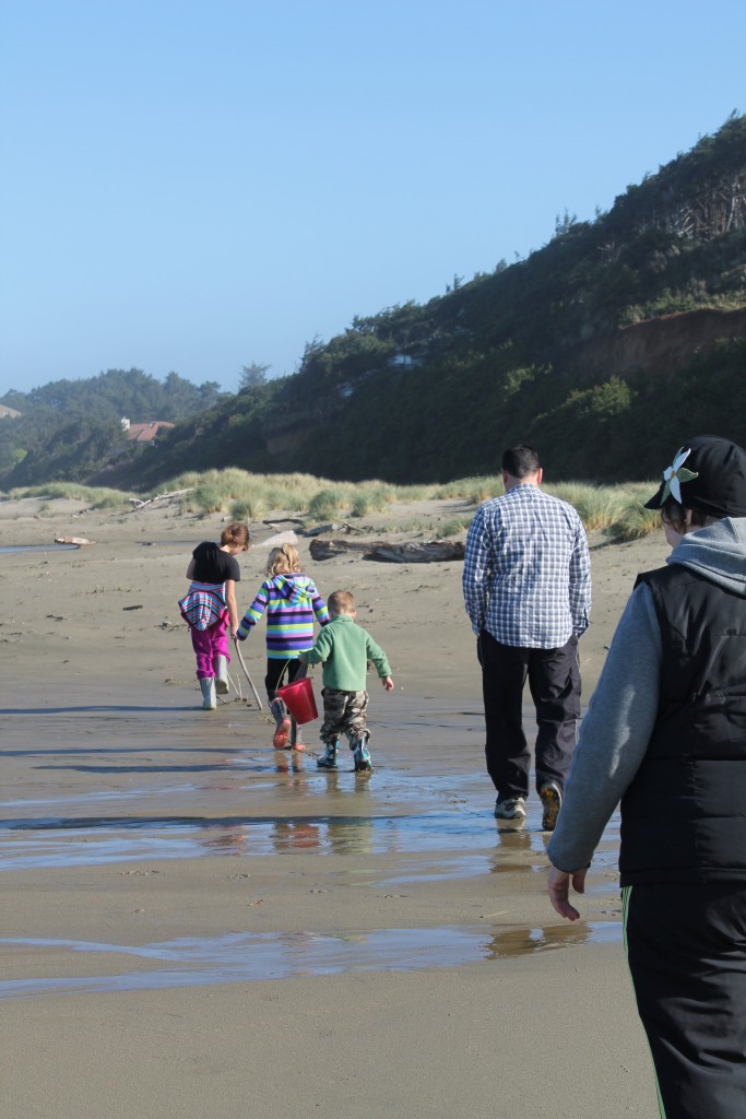 family with three kids walking in a line down a beach