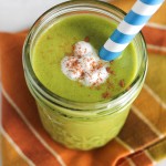 a mason jar filled with a creamy green smoothie with a dollop of coconut cream and sprinkle of cinnamon