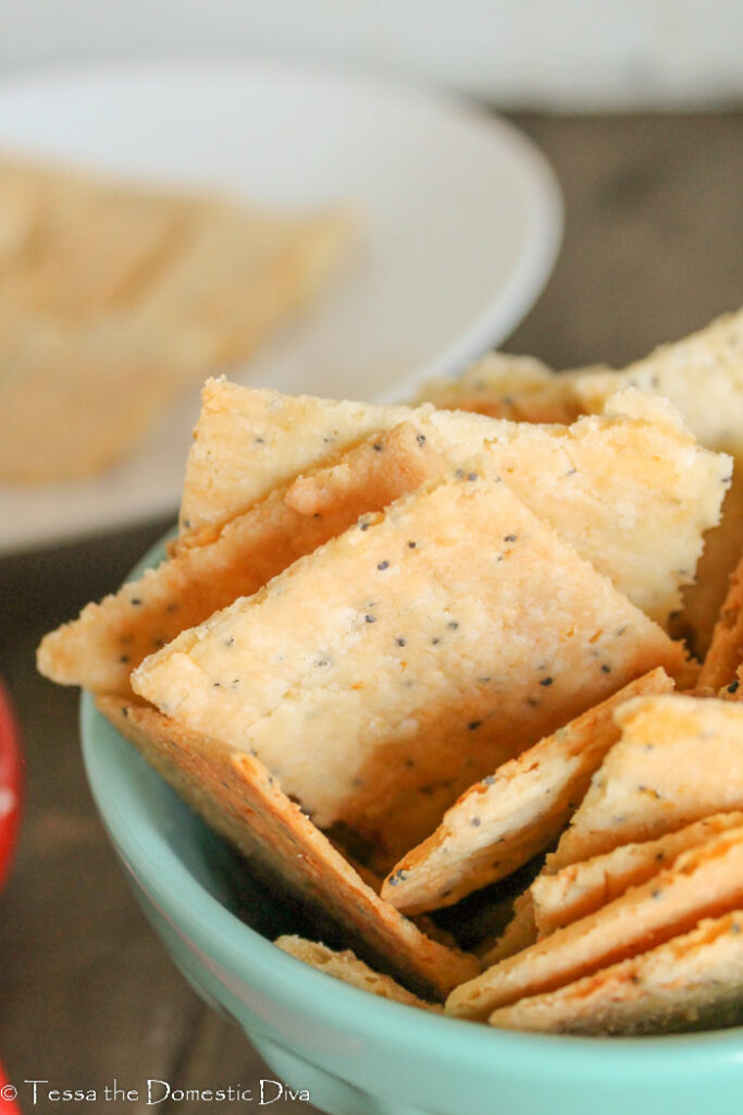 close up of some cheese crackers standing up in a turquoise bowl