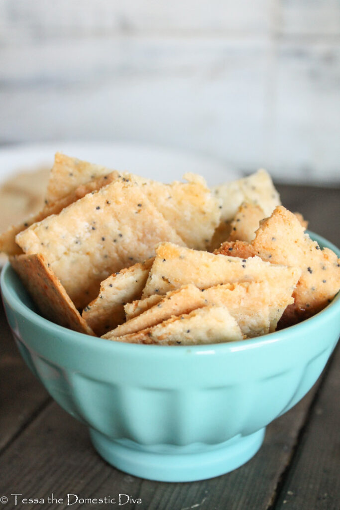 a small blue bowl filled with homemade cheese crackers with a white background