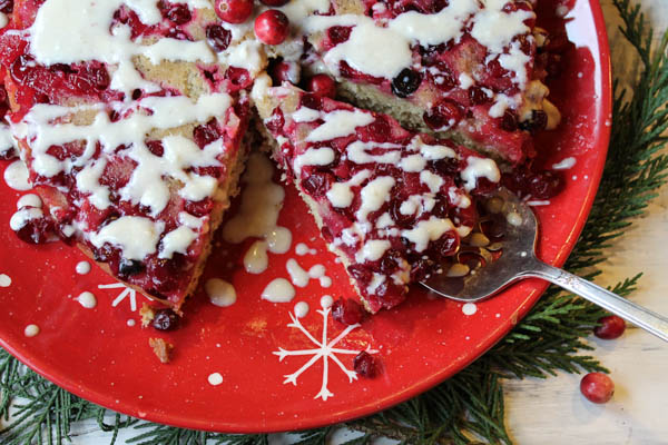 overhead view of cranberry cake with a triangle slice removed and another of a silver serving spatula