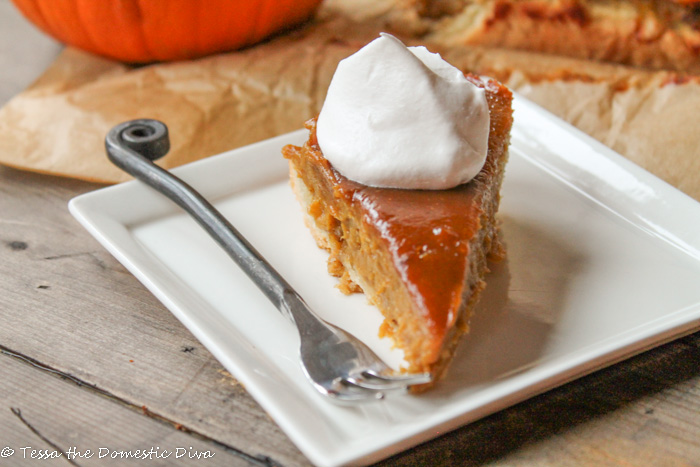 a slice of pumpkin pie on a white plate with a dollop of whipped cream