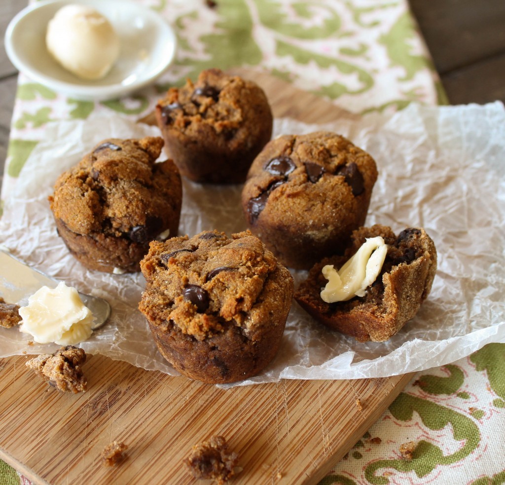 mini sweet potato muffins with a pat butter arranged on a wooden board with a paleo green linen