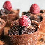 a grouping of mini no bake chocoalte tarts in a nut crust with a fresh raspberry topping and a white background