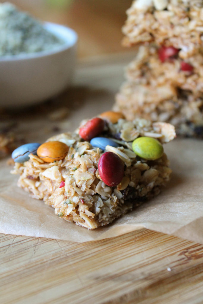 homemade granola bars with/ natural dye m & m's on a wooden board.