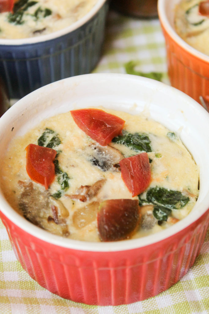 three colored ramekins with individual quiches with basil and heirloom tomatoes