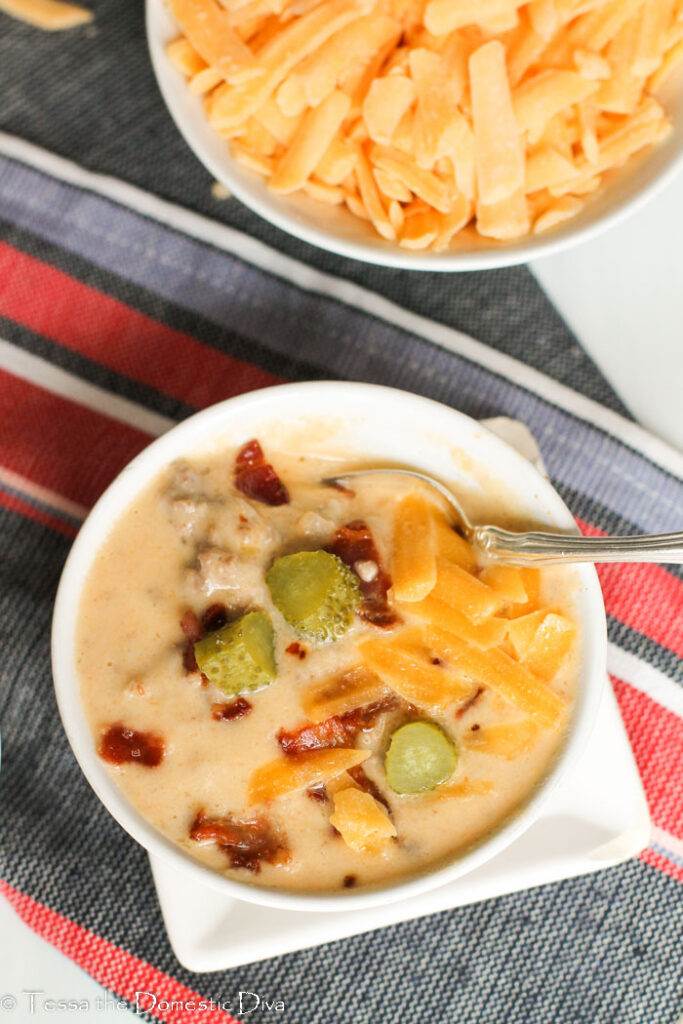 overhead view of a single white bowl with a cheesy hamburger soup.