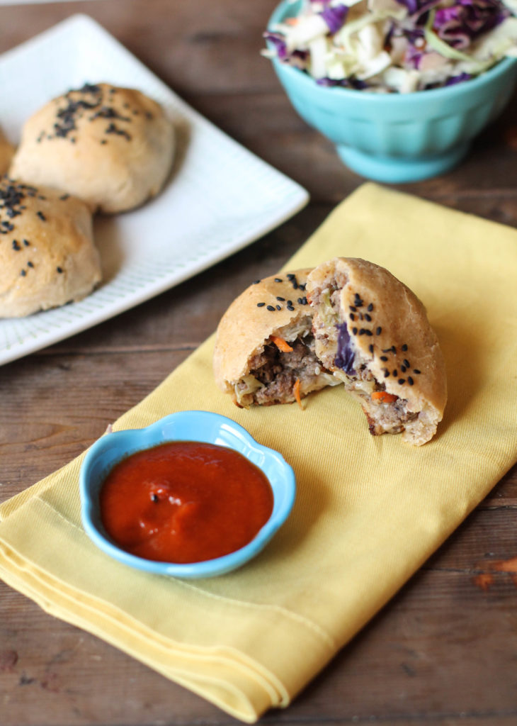 vertical image of a sliced whole 30 paleo chinese baked bao bun from above on a butter yellow napkin