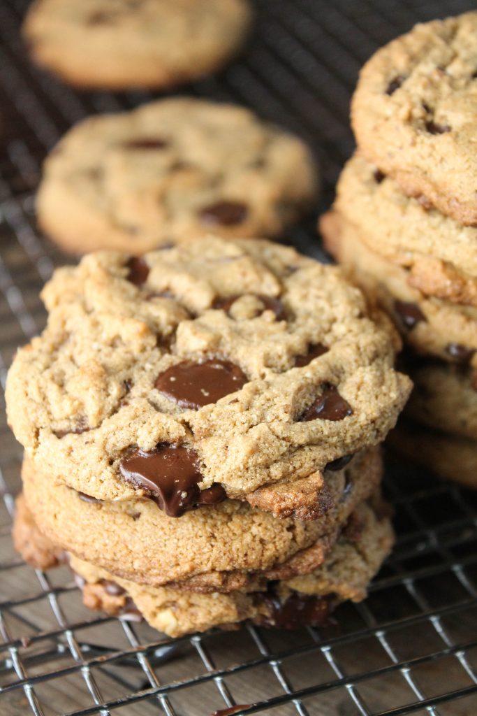 vertical image of 3 stacked best paleo chocolate chip cookies with melty chocolate on a metal cooling rack