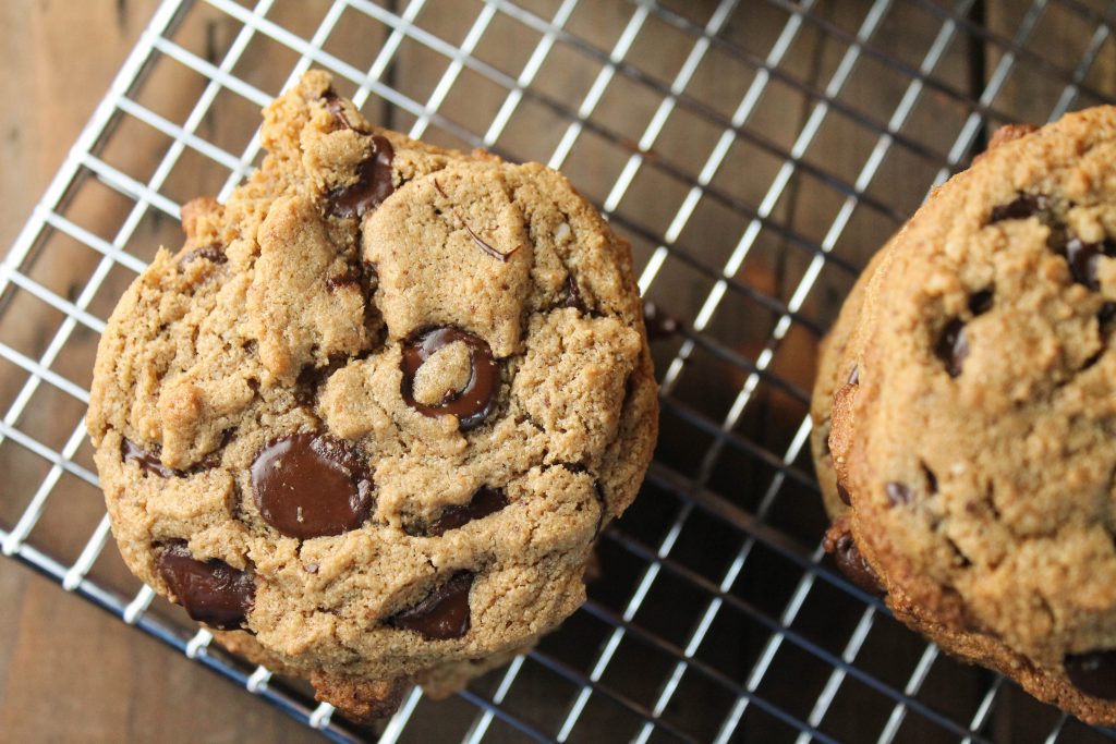 overhead view of a chocolate chip studded cookie atop a stainless steel cooling rack