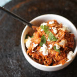 instant pot shredded chicken tings in a small white bowl topped with cilantro and cotija cheese from above