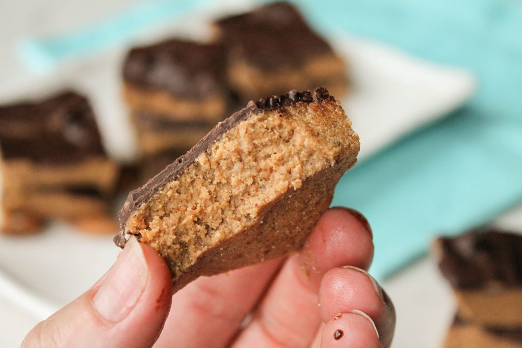 close up of a handheld chunk of chocolate topped low-carb superfood protein bars made with collagen.