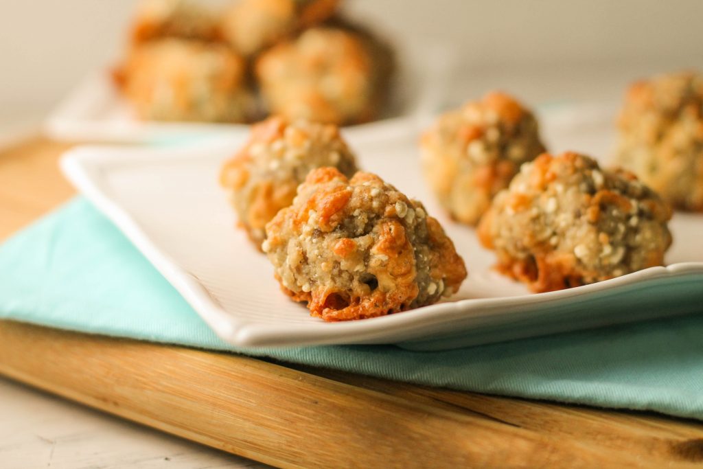 paleo sausage cheese balls on a white plate with golden cheese and a turquoise cloth