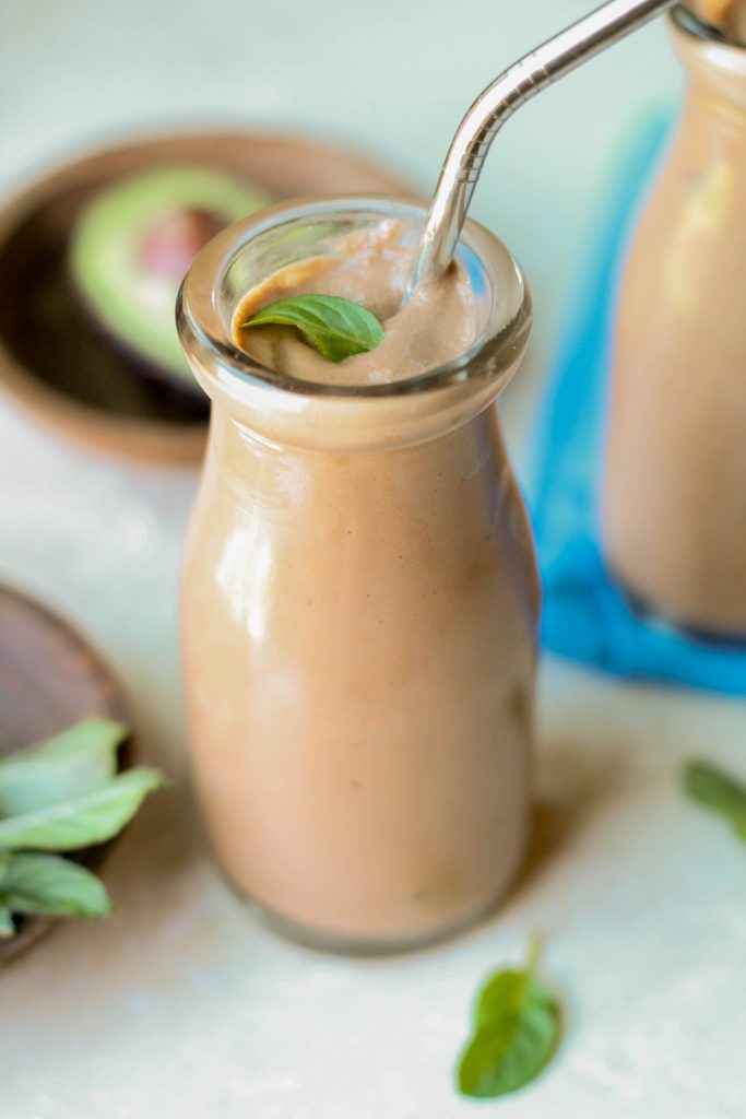 creamy keto chocolate shake in an old fashioned milk jar with a stainless steel straw and a fresh mint leaf garnish