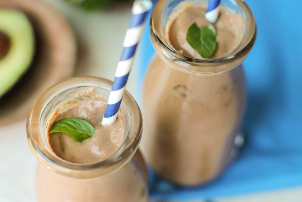 close up aerial view of a two glasses filled with a creamy chocolate avocado shake