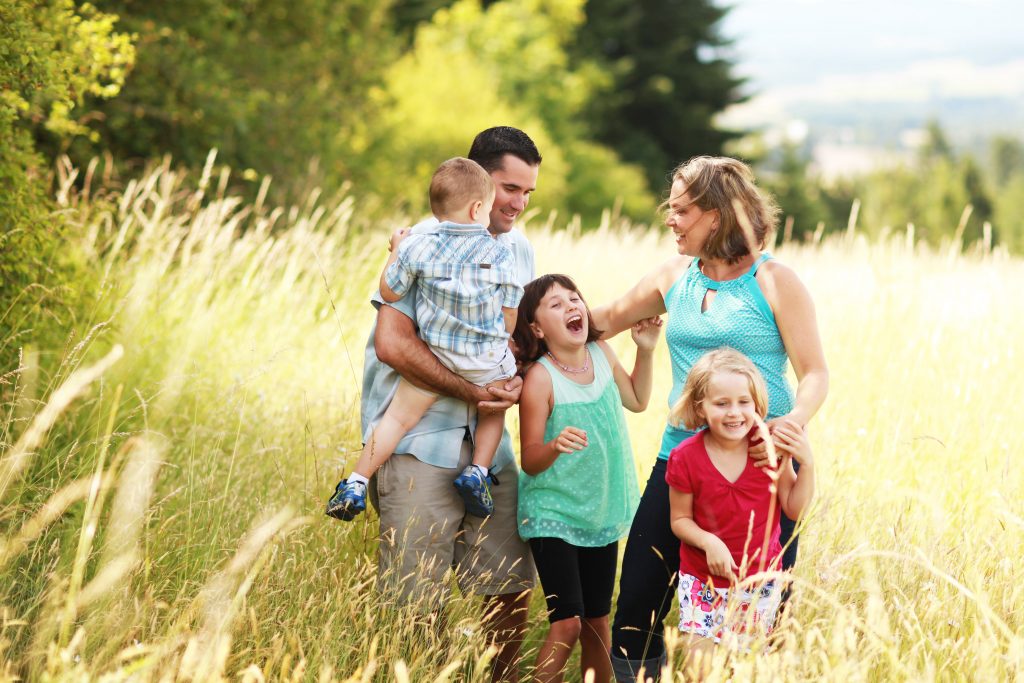 family of 5 with two girls and boy in grass field