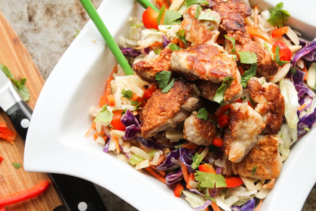 sesame coated chicken bites served atop a Asian slaw from above