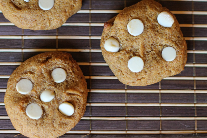 overhead view of white chocolate topped pumpkin cookies on a dark woven mat