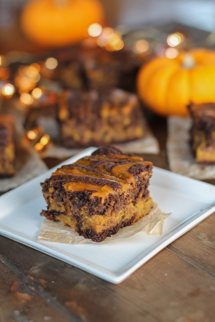 moody low level lighting of a swirled chocolate and pumpkin brownie on a white square plate with glowing amber lights