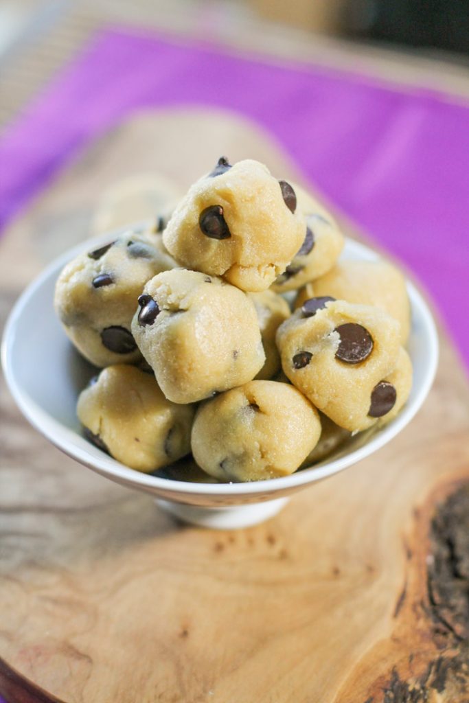 a white bowl filled with chocolate chip cookie doughs balls.