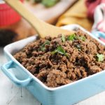 a blue and white ceramic dish filled with savory ground meat and a cilantro garnish