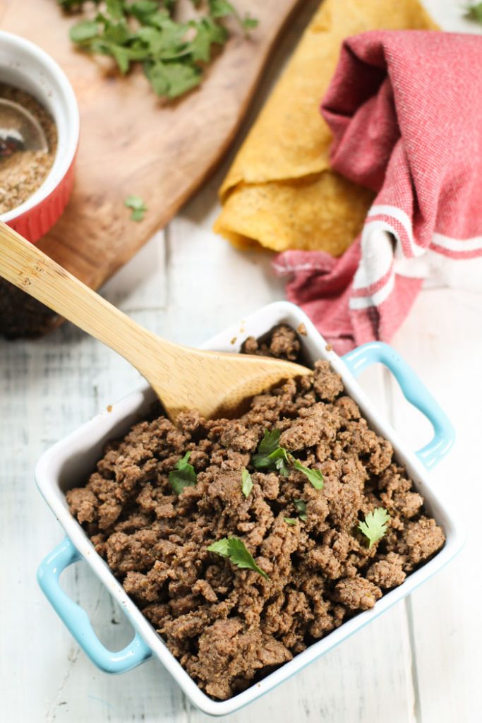 Birdseye view of easy taco seasoned ground beef in a square turquoise dish with handles and wooden serving spoon.