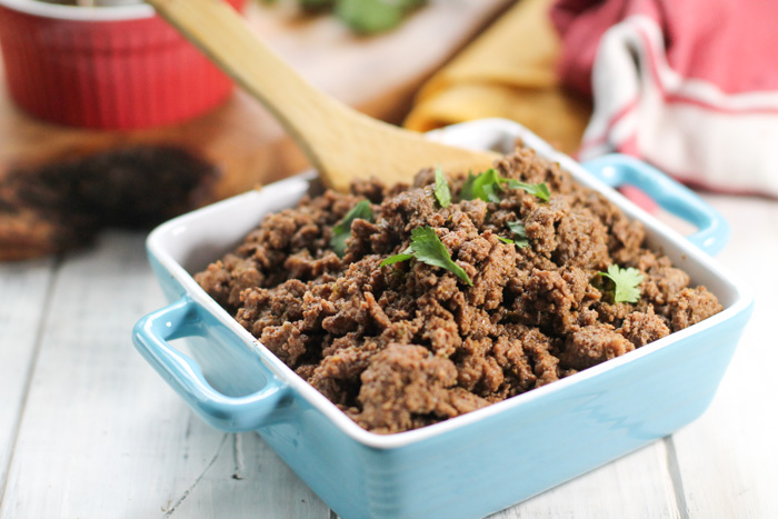 a blue and white ceramic dish filled with savory ground meat and a cilantro garnish