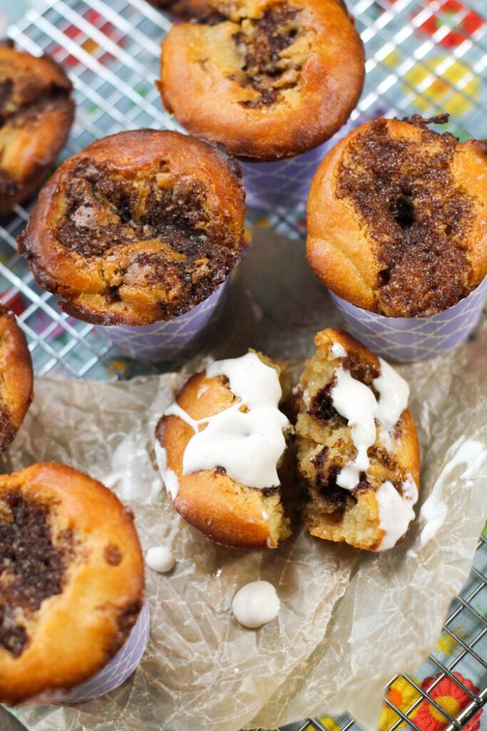 overhead view of a cinnamon roll muffins with a drizzle of cream cheese glaze atop a cooling rack