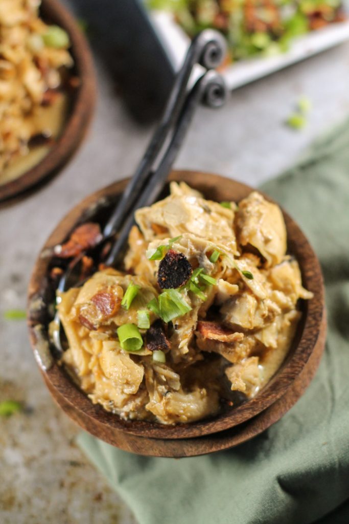 stacked dark wooden bowls filled with tender shredded chicken in a a creamy bacon sauce from overhead