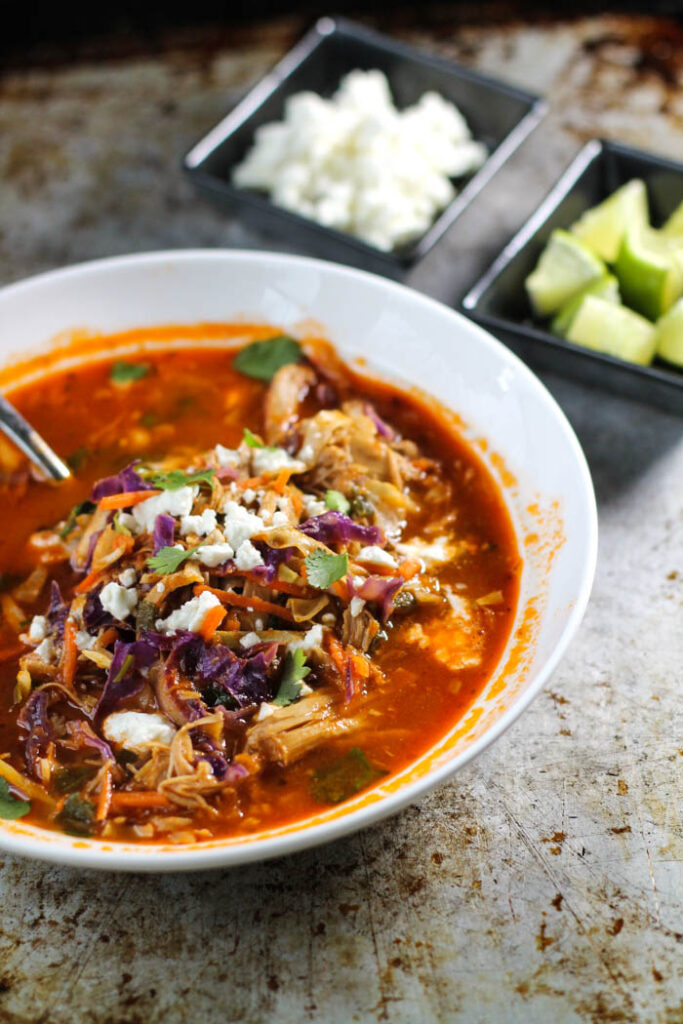 a white bowl from overhead filled with a low carb tortilla soup with fresh cabbage shreds and crumbled white cheese