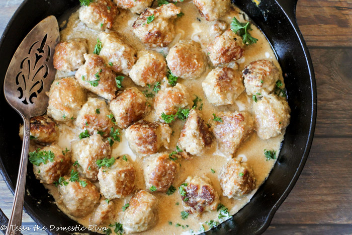 an overhead view of a cast iron skillet filled with golden turkey meatballs coated in a creamy sauce