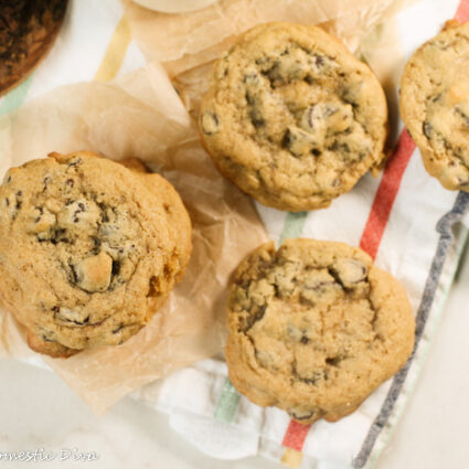 birds eye view of stacks of chewy chocolate chip cookes on a white a color striped linen