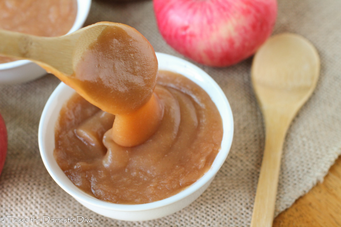 a spoon dripping with homemade creamy applesauce with peels