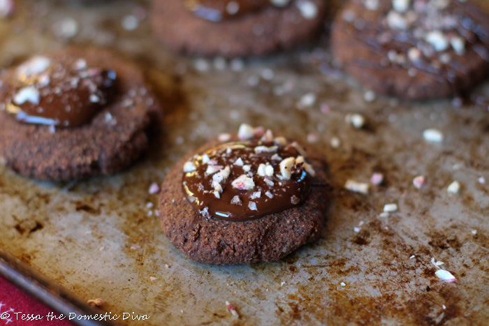 chococlate mint thumbprint cookies filled with a creamy ganche and topped with natural crushed candy canes