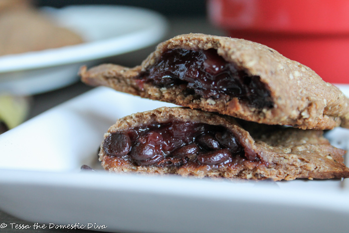 close up of a halved sweet empanada filled with berries and chocolate on a white plate