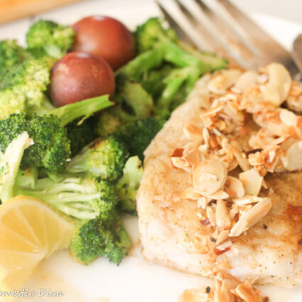 birdseye view of a crispy fillet of cod topped with a butter, lemon, garlic, and almond sauce on a white plate