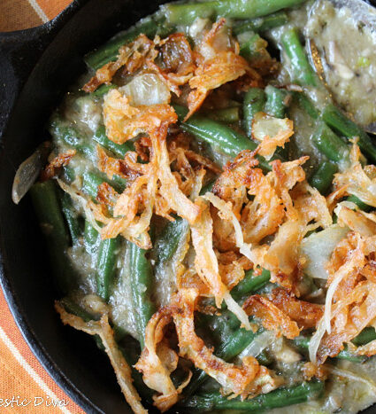 cast iron skillet filled with blancehd green beans in a creamy mushroomsauce and crispy onion topping