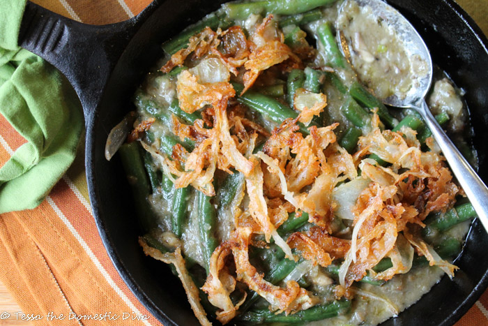cast iron skillet filled with blancehd green beans in a creamy mushroomsauce and crispy onion topping