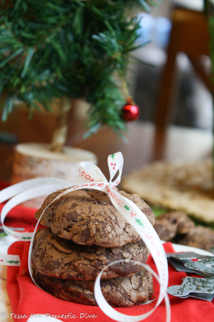 three glossy chocolate cookies stacked with a white Christmas ribbon tied around