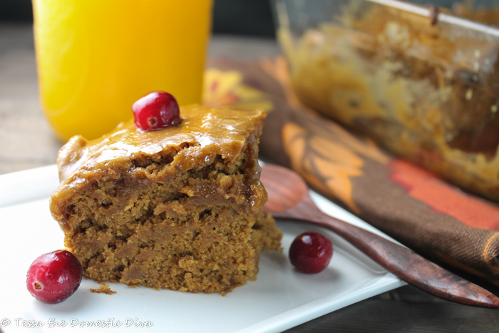 a square of pumpkin cake on a white plate with fresh pumpkin puree and cranberries