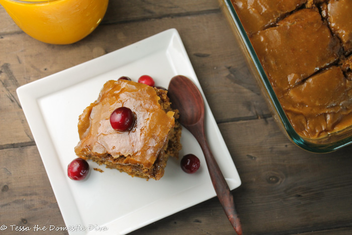 birds eye view of shiny caramel glazed square of moist pumpkin cake with a fresh cranberry on top