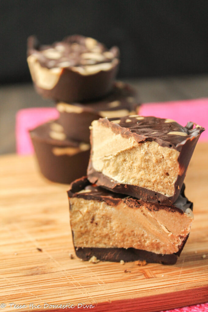 a halved homemade peanut butter cup on a wooden cutting board drizzled with chocolate