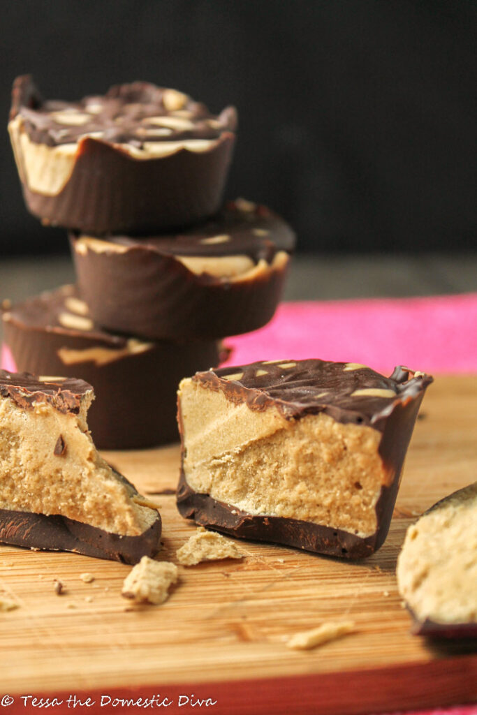 several healthy peanut butter cups arranged on a wooden cutting board with a pink cloth