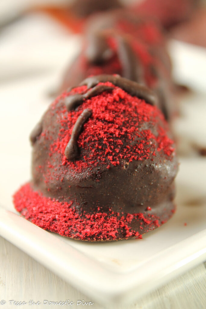 chocolate truffles dusted with raspberry powder face on on a white plate