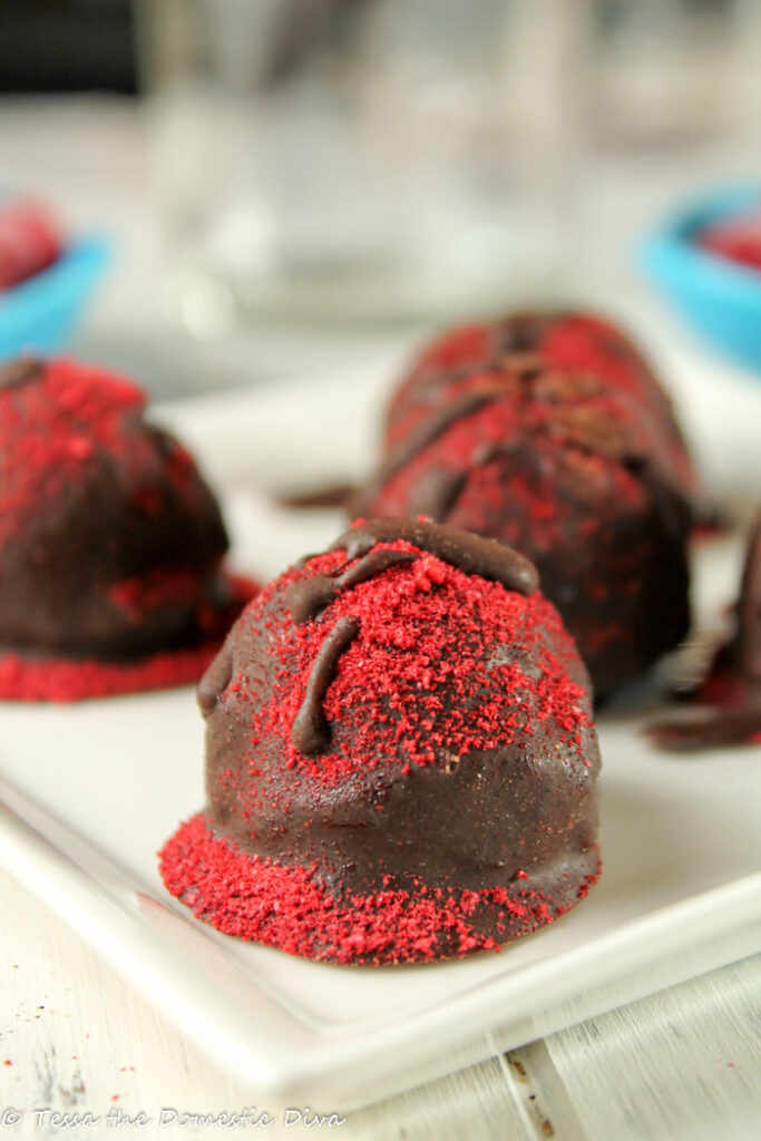 homemade truffles on a white plate with a dusting of raspberry powder