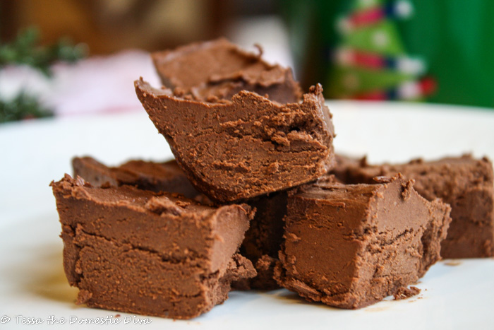 square of chocolate fudge on a white plate with a Christmas background