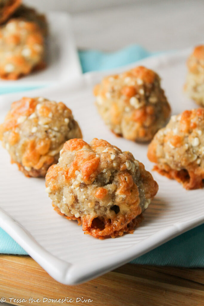 sausage cheese balls on a white plate at eye level close up with turquoise background