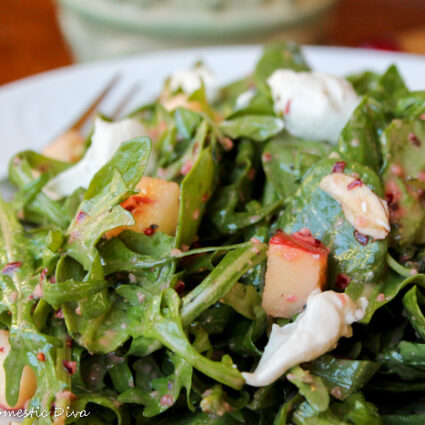 close up of mixed greens drssed in a bright red cranberry