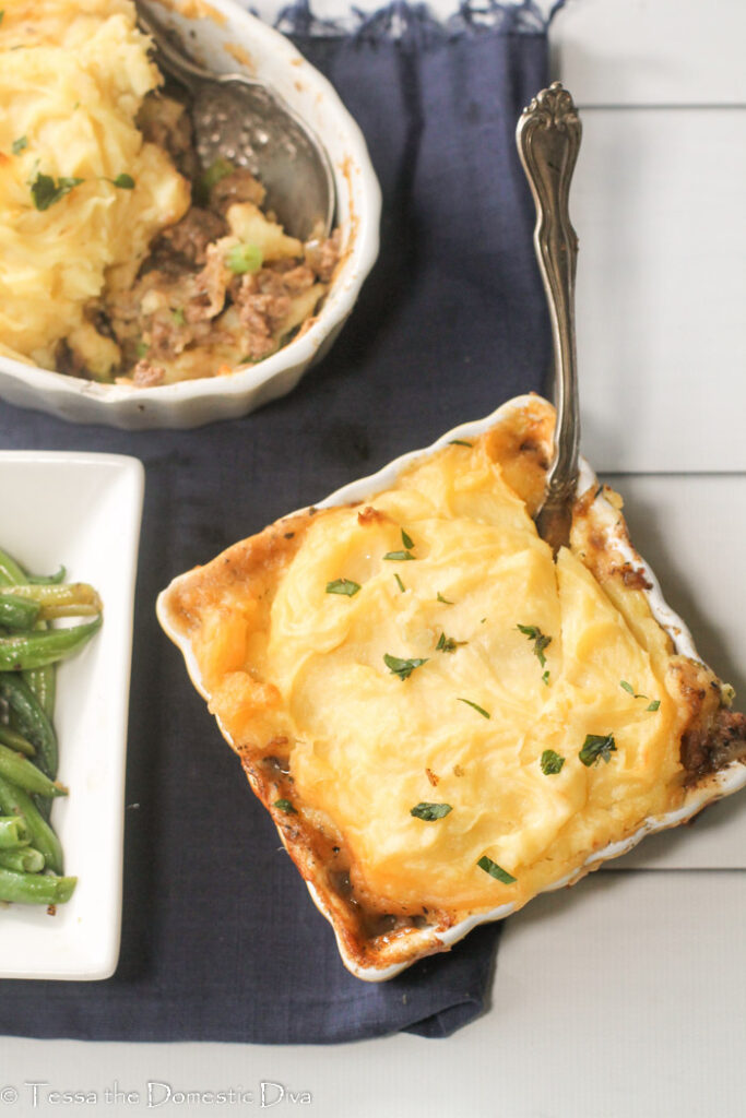 birdseye view of two ceramic baking dishes fill with ground beef and a mashed potato topping